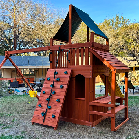 Backyard playset with lower level playhouse and wood roofs.